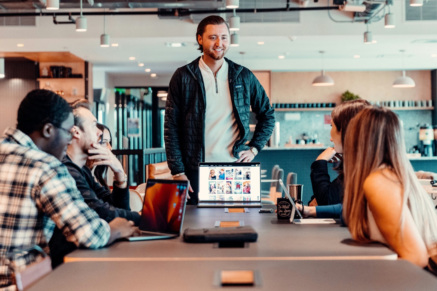 Professional team collaborating in modern office with laptops and whiteboard